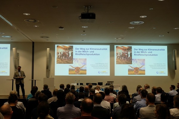 Participants à une conférence, une présentation est diffusée en arrière-plan.